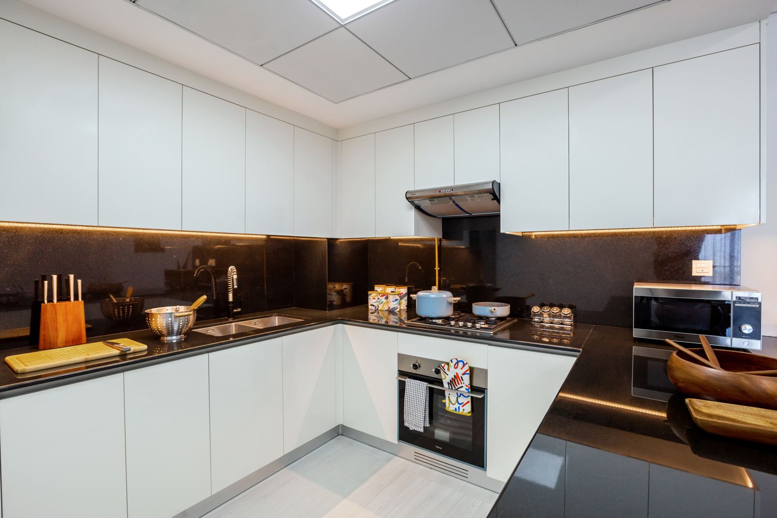 White kitchen with black stone worktops and Teka oven, hob and microwave