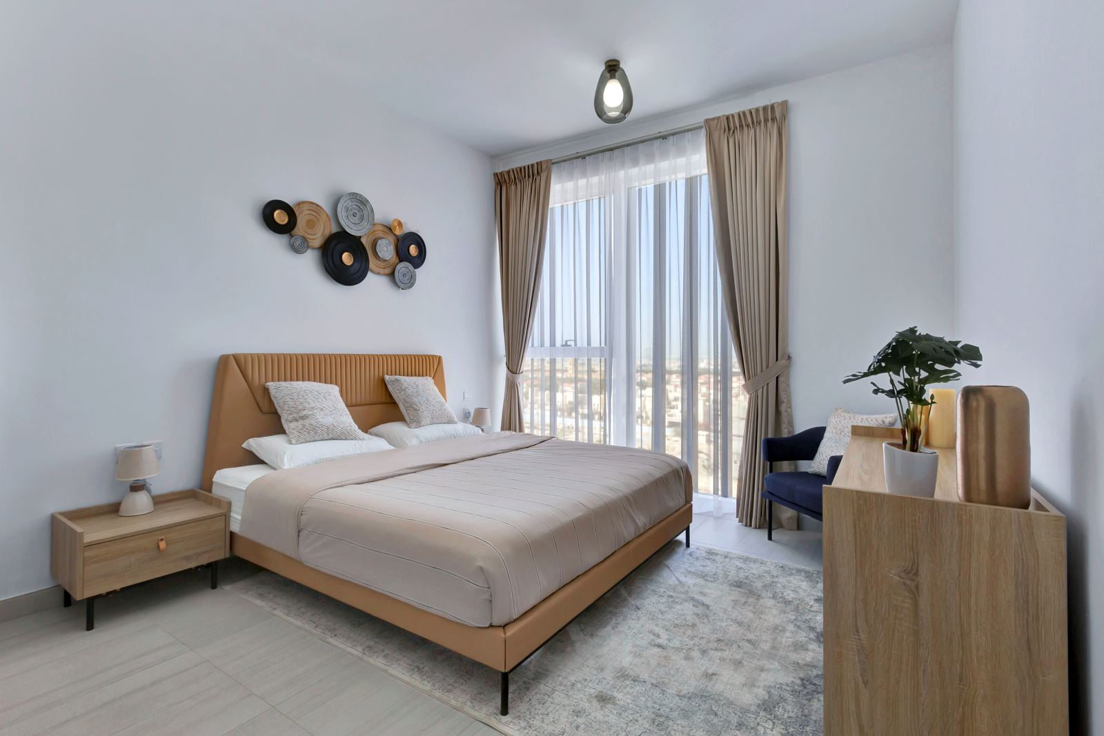 Bedroom with tan upholstered bed and floor-to-ceiling window