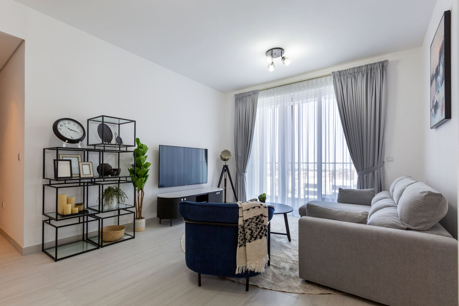 Living room with grey sofa, full-height window and sheer curtains