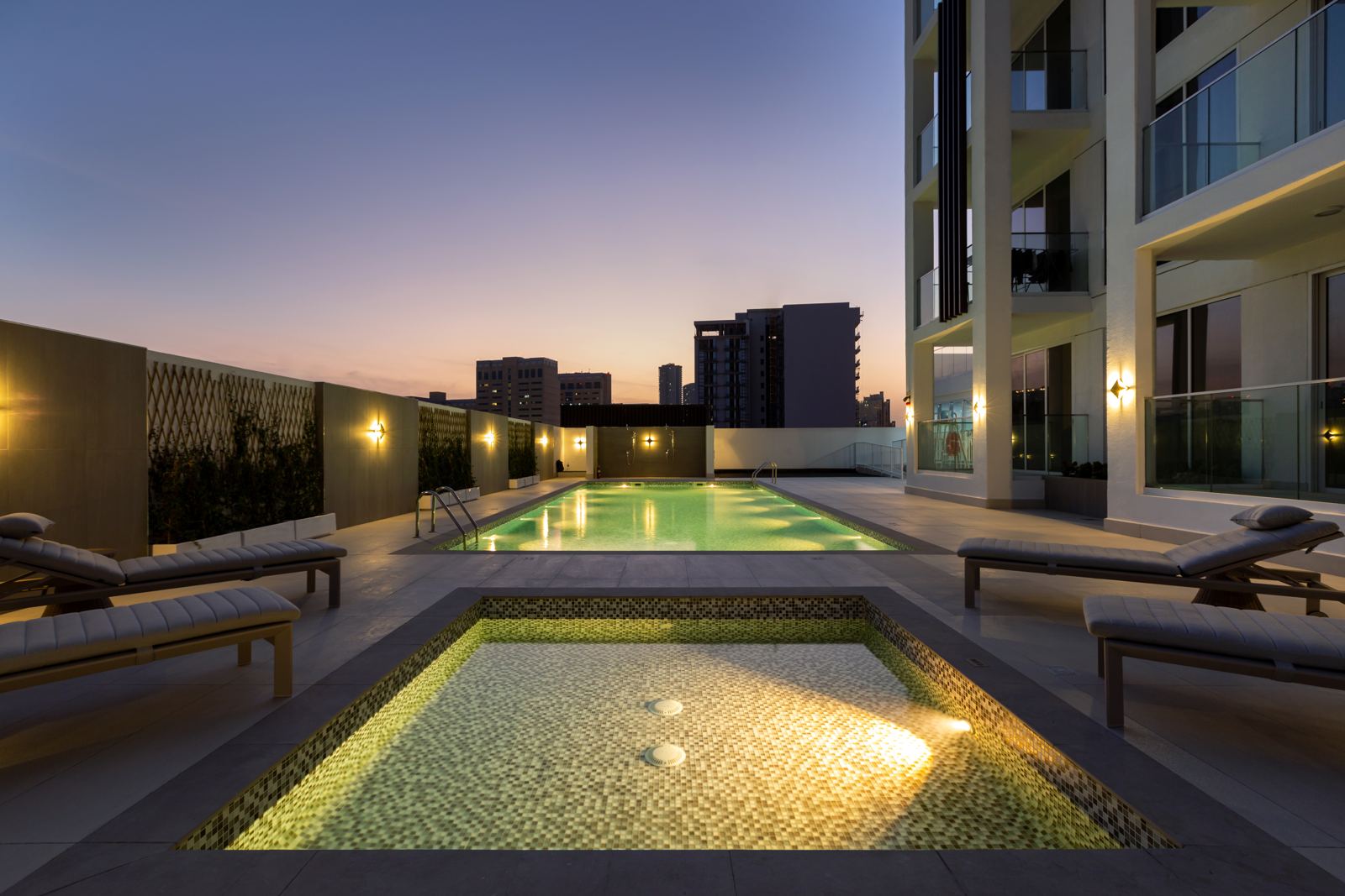 Kids' pool in the foreground and the lit adults' pool behind at dusk